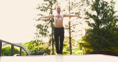 Atletik adam yoga pozisyonu alıyor ve havada el kaldırırken yoga yapıyor.