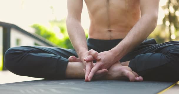 Homem sentado na posição de lótus no tapete de ioga na plataforma de madeira no verão.Atleta meditando sozinho — Vídeo de Stock