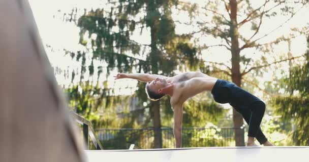 Deportista realizando yoga pose de equilibrio por una mano en la naturaleza.Hombre fortaleciendo los músculos del cuerpo de la espalda — Vídeo de stock