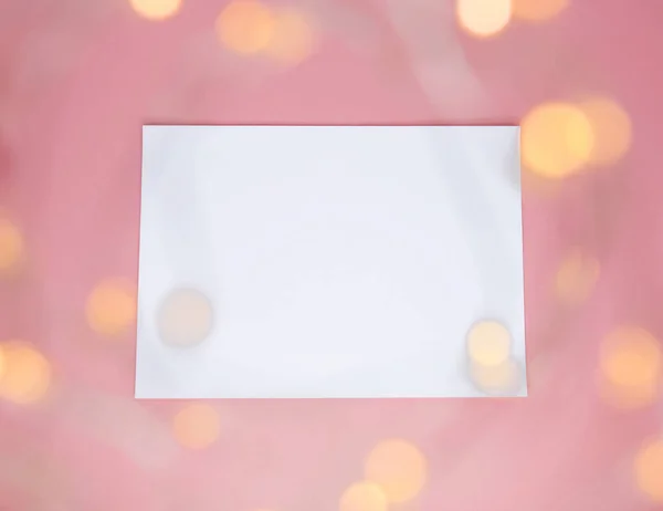 Witboek over een roze achtergrond met onscherpe schitteringen. — Stockfoto