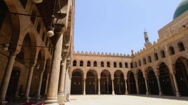 Süslü kemer ve kolonlara sahip tarihi Mısır camii avlusu, bir seyahat ziyareti sırasında güzel İslami mimari eserleri sergiliyor.