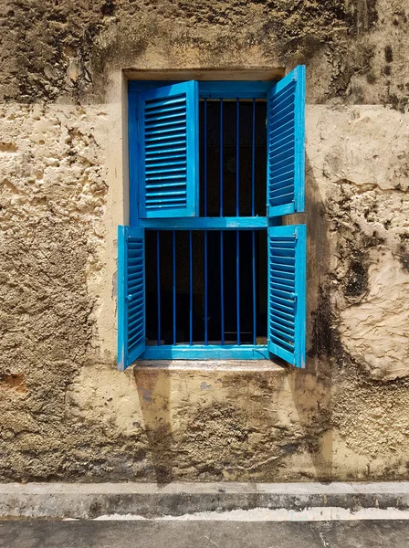 open blue window with shutters in the window opening of an old building or house, a fragment of the facade, texture