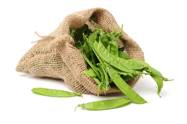 Guisantes verdes en bolsa tejida sobre blanco — Foto de Stock