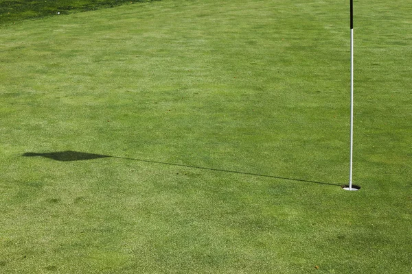 Flagstick τρύπα σε μια τοποθέτηση πράσινη σε μια σειρά μαθημάτων γκολφ. — Φωτογραφία Αρχείου