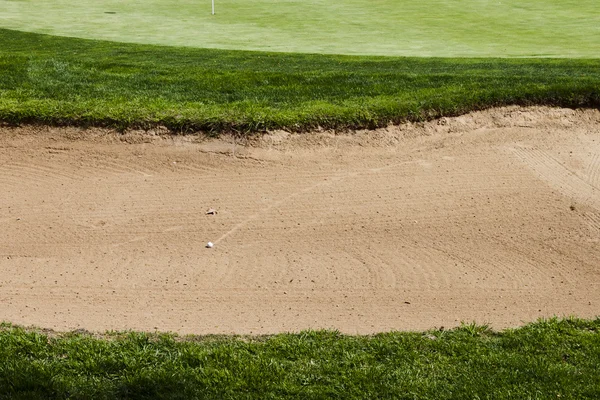 Bola de golfe em um bunker perigo armadilha de areia em um campo de golfe . — Fotografia de Stock
