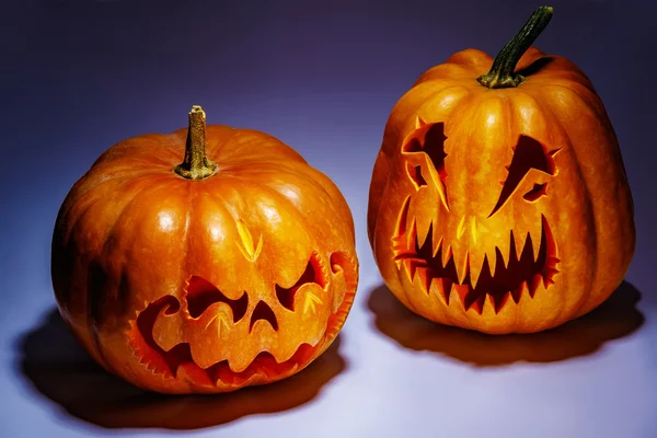 Deux effrayantes citrouilles d'Halloween avec des ombres sur un backgrou coloré — Photo