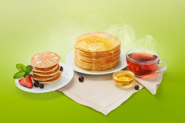 Stapel frisch gebackener Pfannkuchen mit Butter, Honig und heißem Tee. — Stockfoto