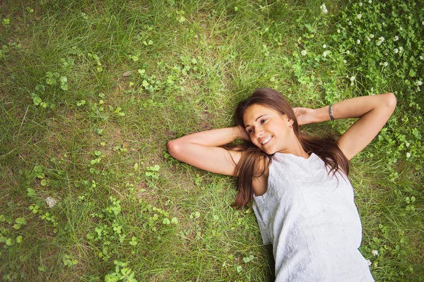 Young brunette woman enjoying the lying on her back on the green — Stock Photo, Image