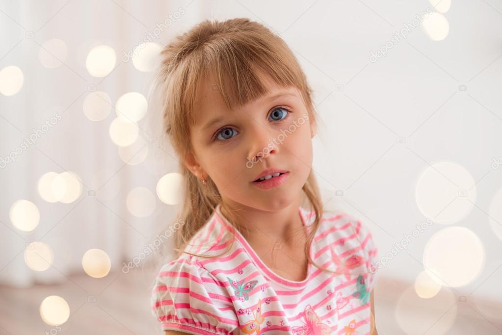 Cute little girl at home. Holiday lights around.