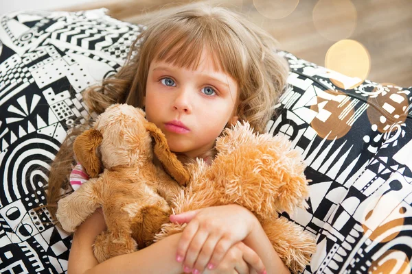 Meisje met een zacht speelgoed thuis. — Stockfoto