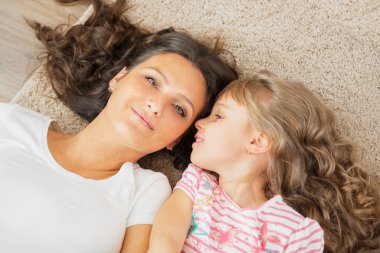 Anne ve küçük kızı beraber yalan annesinin kulağına fısıldayan