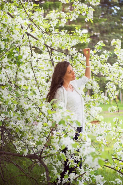 Chica morena de primavera de pie al aire libre en los árboles en flor. Beautif. — Foto de Stock