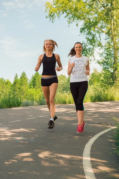 Two young woman doing sports outdoors in a park on sunny summer — Stock fotografie