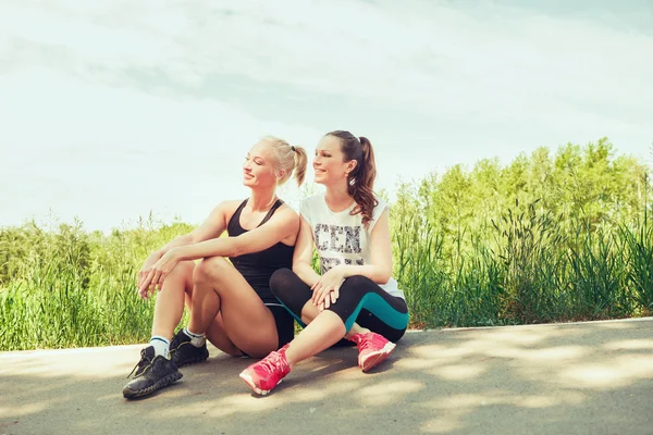 Dos mujeres jóvenes sentadas al aire libre en un parque en el soleado día de verano — Foto de Stock