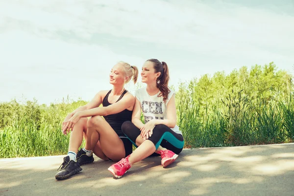 Two young women  seating outdoors in a park on sunny summer day — Zdjęcie stockowe