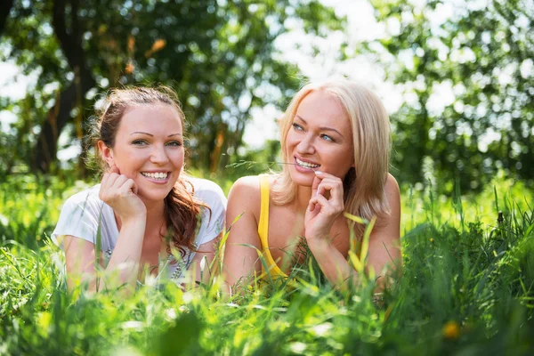 Two cute young women lying in the grass on summer sunny day outd — Stock Photo, Image