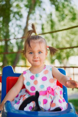 Sevimli küçük kız yaz güneşli bir günde çimlere oturup.