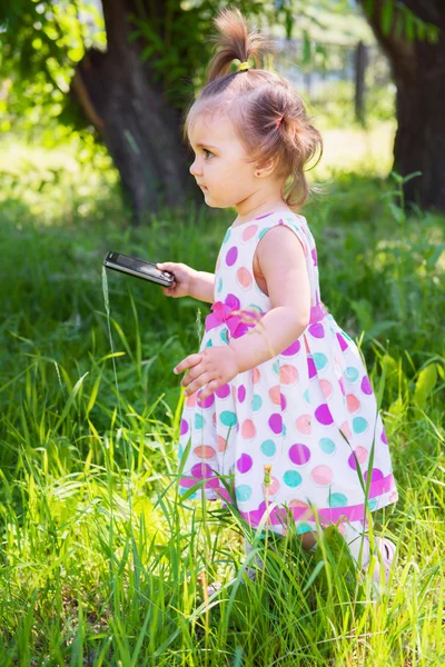 Cute little girl sitting on the grass on a summer sunny day. — Stock Photo, Image