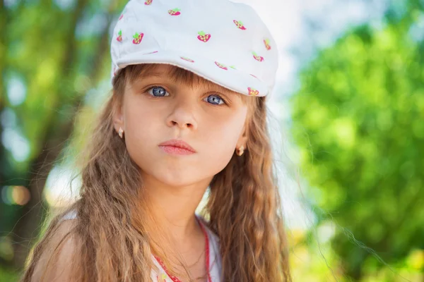 Cute little girl sitting on the grass on a summer sunny day. — Stock Photo, Image