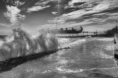 Dalgalar kıyıya vurur ve setin üzerinde yumuşak bir battaniye gibi yuvarlanır. Deniz suyu parlak güney güneşinin ve güzel bulutların altında narin renklerle parıldıyor.