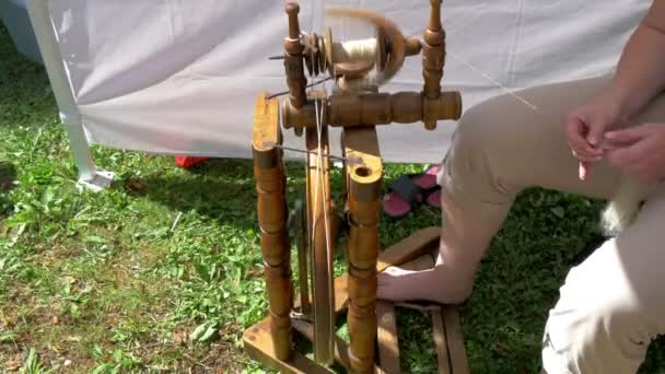 Un homme pédale la roue tournante pour créer un fil GH4 — Video