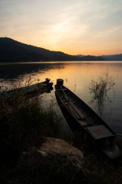 Gün batımında gökyüzü olan bir gölde kayık.