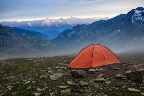 Base camp set in Alpine background. Ten set on hill i Alps mountains. Tourist shelter camp in high mountains.