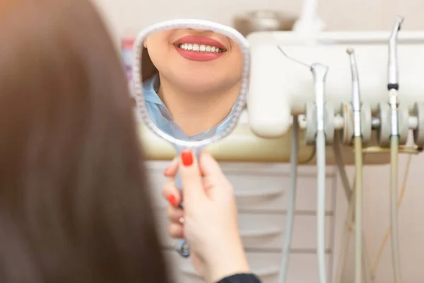 Genç beyaz kadın hasta aynaya bakıp gülümsemesine hayran.