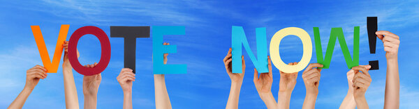 Люди, держащие в руках разноцветные прямолинейные слова, голосуют сейчас за голубое небо
