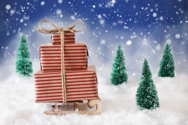 Різдвяні санки на снігу з синім фоном, сніжинки та зірки — стокове фото