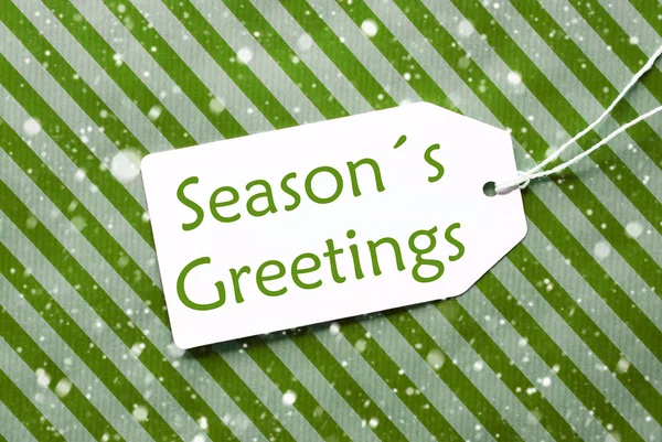 Label op groene inpakpapier met sneeuwvlokken, tekst Seasons Greetings — Stockfoto