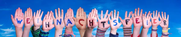 Kinderhände bauen Wort Weihnachtsfeier bedeutet Weihnachtsfeier, blauer Himmel — Stockfoto