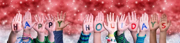 Gyerekek kezek épület Word Boldog Ünnepeket, Red Christmas Háttér — Stock Fotó