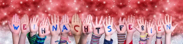 Las manos de los niños Weihnachtsferien significa vacaciones de Navidad, fondo rojo de Navidad — Foto de Stock