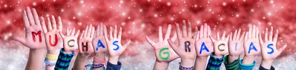 Mãos de crianças Muchas Gracias significa obrigado, fundo de Natal vermelho — Fotografia de Stock