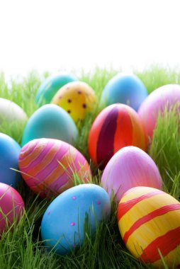 Yeşil çimenlerin üzerinde birçok renkli Paskalya yumurtaları