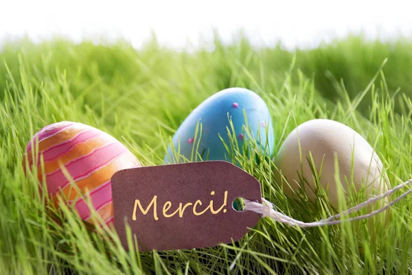 Glad påsk bakgrund med färgglada ägg och etikett med fransk Text Merci — Stockfoto