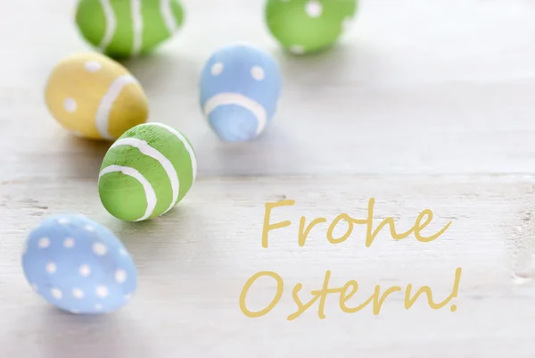 Huevos de Pascua azules verdes y amarillos con texto alemán Frohe Ostern significa feliz Pascua — Foto de Stock