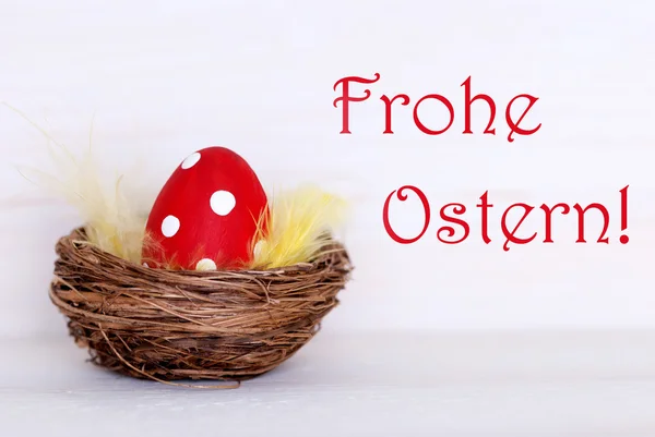 Um ovo de Páscoa vermelho em ninho com Frohe Ostern alemão significa feliz Páscoa — Fotografia de Stock