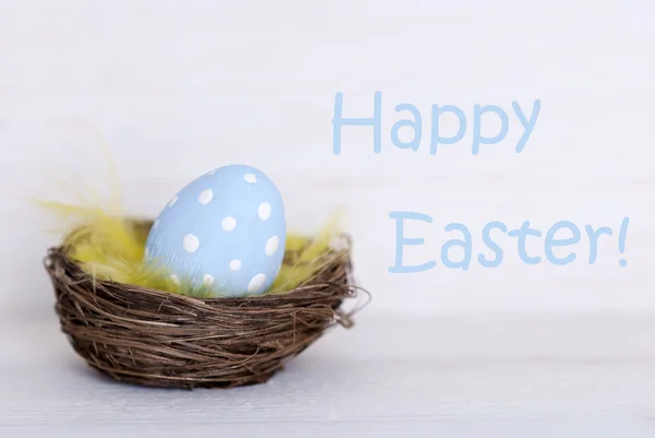 Ein blaues Osterei im Nest mit frohen Ostern — Stockfoto