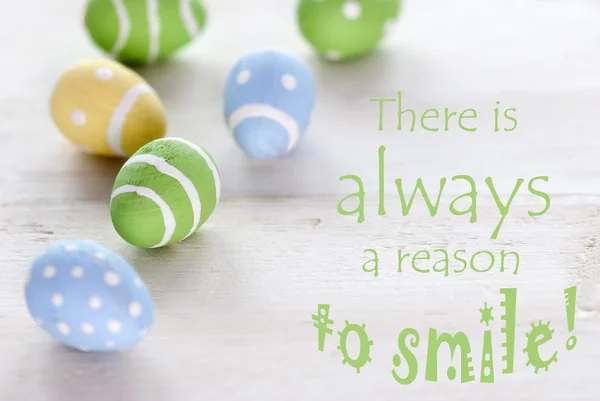 Huevos de Pascua azules verdes y amarillos con cita de vida Siempre hay una razón para sonreír — Foto de Stock