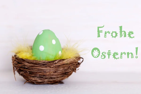 Een groene Easter Egg In Nest met Duitse Frohe Ostern betekent vrolijk Pasen — Stockfoto