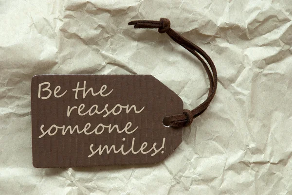 Etiqueta marrón con la razón de la cita Alguien sonríe fondo de papel —  Fotos de Stock