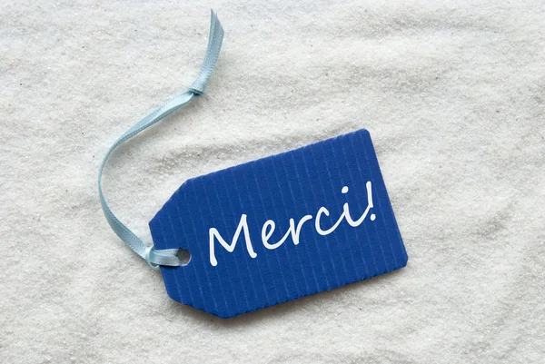 Merci bedeutet Danke auf blauem Etikett Sand Hintergrund — Stockfoto