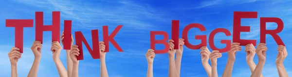 Las manos de la gente sosteniendo la palabra roja Piense en un cielo azul más grande — Foto de Stock