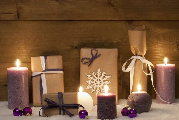Regalos de Navidad púrpura con velas y bolas, nieve Imágenes de stock libres de derechos