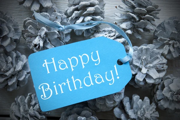 Etiqueta azul claro en los conos de abeto con feliz cumpleaños — Foto de Stock