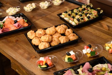 Tek kullanımlık yiyecek ambalajı. Sebze salataları, et, siyah plastik tabaklar içinde tatlılar.