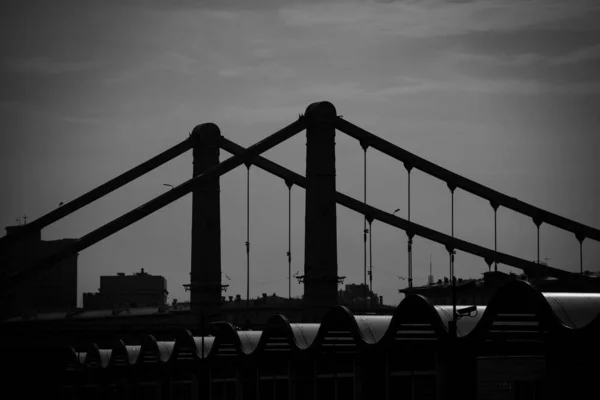 Black and white, suspension bridge connects to highway over river