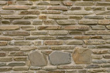 Duvardaki tuğlaların dokusunu vahşi taş arkaplan şeklinde. Gölgeli ve koyu renkli bej ve kahverengi tonlarda. Duvar arkaplanı için taşa bakıyor.